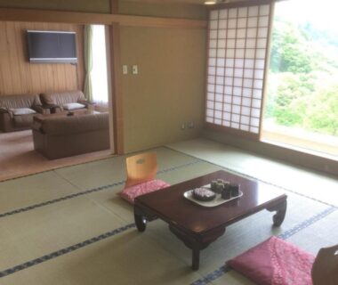 Tatami room with low table, zabuton, shoji, and separate sitting area with sofa at Higashiyama Park Hotel Shinfugetsu Fukushima