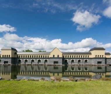 Long lakeside hotel with arched facade reflected in pond at Higashiyama Park Hotel Shinfugetsu, Fukushima, Tōhoku
