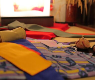 Folded colorful yukata with obis and wooden geta inside Hiina ryokan in Shizuoka, Chūbu, Japan