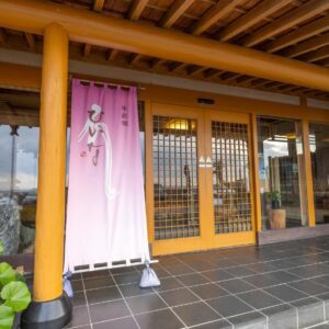 Pink noren, wooden columns and lattice sliding doors at Hiina ryokan entrance in Shizuoka, Chūbu region