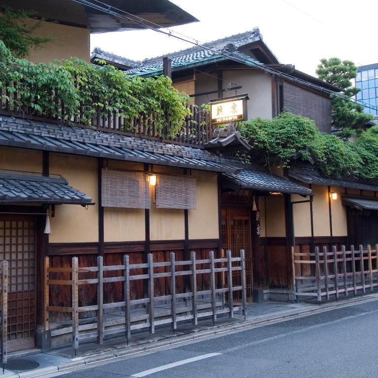 Traditional wooden facade Hiiragiya Kyoto Exterior of Hiiragiya with wooden lattice, tiled roof, lanterns and greenery along a Kyoto street