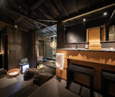 Dimly lit wooden onsen room with soaking tub and low seating at Hikyou Shirakawagensen Sansou Takefue Kumamoto