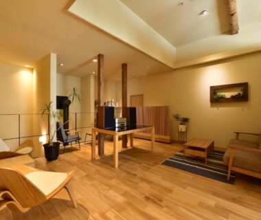Lounge with warm wood flooring, low tables, armchairs and soft ambient lighting at Hinatamikan in Gunma, Kantō