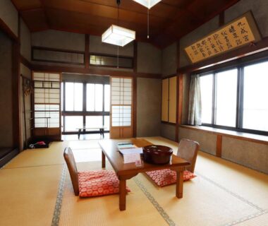 Traditional tatami room with low table, cushions, shoji screens and large windows at Hinode Ryokan, Mie