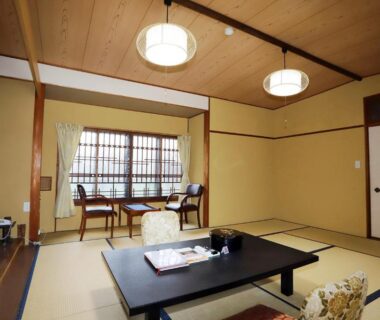 Traditional tatami room with low table, floor cushions, shoji window and wooden ceiling at Hinode Ryokan in Mie