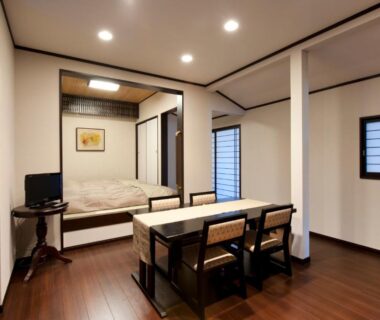 Wood-floor room with dining table and raised bed platform at Hinode Ryokan in Mie