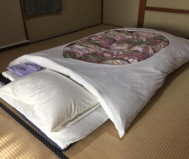 Neatly arranged futon and pillow on tatami mat in Hinodeya ryokan room