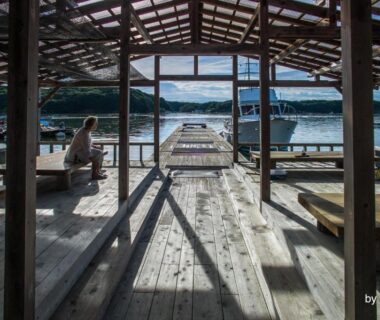 Covered wooden pier with benches, boats and distant mountains at Hiogiso in Mie, Kansai