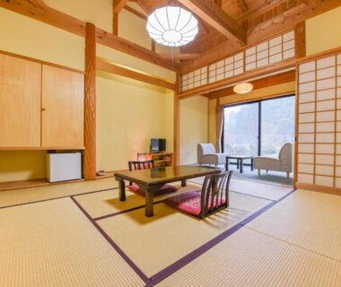Spacious tatami room with low table, zabuton chairs, shoji screens and seating area at Hirayama Onsen Ryokan Kadoya, Kumamoto