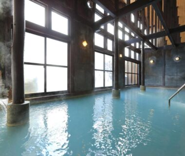Spacious indoor onsen with wooden beams and large windows at Hirayunomori in Gifu, Chūbu, Japan