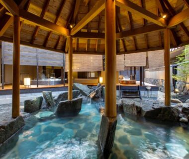 Covered onsen pools with wooden beams and rock surrounds at Hirugami Grand Hotel Tenshin, Nagano