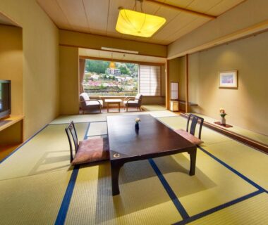 Traditional tatami room with low table, floor cushions, shoji screens and window view at Hirugami Grand Hotel Tenshin, Nagano