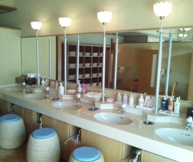 Long vanity with sinks, mirrors, woven stools and toiletries at Hirugami Grand Hotel Tenshin, Nagano