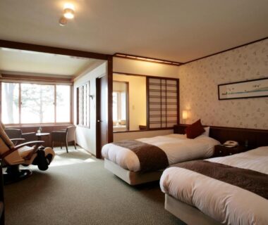 Spacious twin guest room with shoji screens, seating area and garden view at Hokkaido Lakeside Hotel Suimeikaku Japan