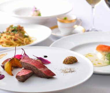 Elegant multi-course plated dinner with sliced meat, pasta and wine in a ryokan dining setting in Hokkaidō