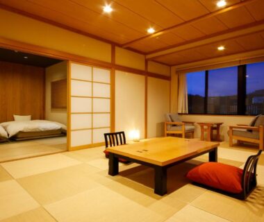 Tatami room with low table, shoji screens and futon bedding in adjoining alcove at Hotel Kikyou, Ishikawa