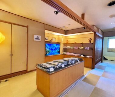 Tatami flooring, shoji doors, wooden display counter with folded garments and warm ambient lighting