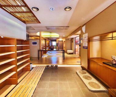 Traditional genkan with wooden shoe shelves, slippers and tatami hallway leading to lobby at Honjin, Shizuoka, Chūbu