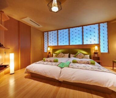 Spacious Japanese-style guest room with low futon beds, shoji-style windows and warm wooden interior at Honjin Hiranoya Kachoan in Gifu