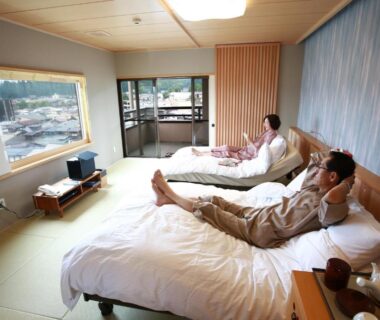 Guests relaxing on beds in a tatami room at Honjin Hiranoya Kofukan, Gifu prefecture