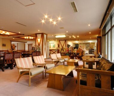 Spacious ryokan lounge with wooden seating, low tables and large windows at Horohoro Sanso, Hokkaidō