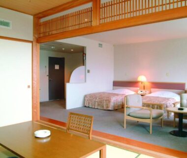 Room with tatami seating area, low table and twin Western beds at Horoshin Onsen Hotarukan in Hokkaidō