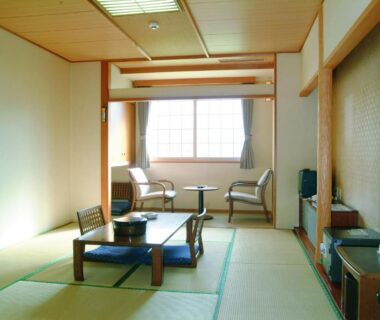 Traditional tatami room with low table, floor cushions and window seating at Horoshin Onsen Hotarukan, Hokkaidō Japan