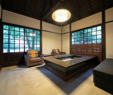 Traditional lounge with sunken seating, wooden beams, lattice windows and bookshelves at Hosenji Kanko Hotel Yumotoya, Oita