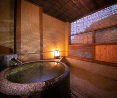Stone soaking tub in wooden indoor onsen room at Hosenji Kanko Hotel Yumotoya, Oita