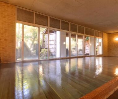 Spacious indoor wooden bath hall with large windows and garden view at Hosenji Kanko Hotel Yumotoya in Ōita