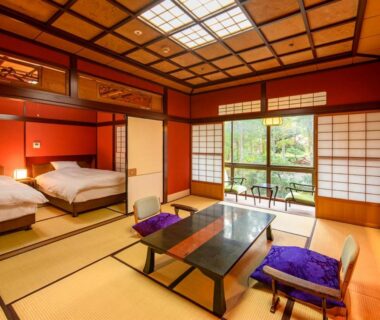 Tatami room with low table, zabuton cushions, shoji screens and two western-style beds overlooking a garden