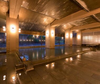 Spacious indoor onsen bath with timber beams and stone floor at Hoshi Ryokan, Ishikawa, Chūbu