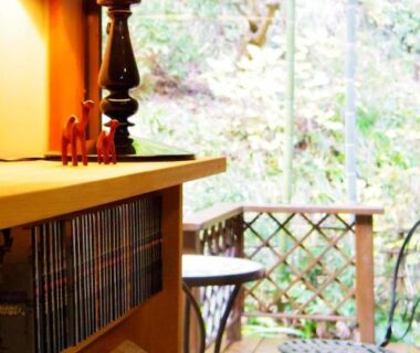 Bookshelf and lamp beside wooden deck with bistro table and garden view at Hoshi Meguri, Shizuoka