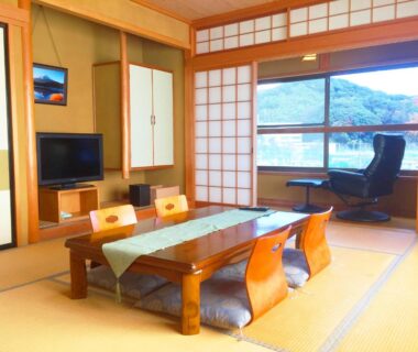 Traditional tatami room with low table, zabuton cushions, shoji screens and mountain view at Hoshi Meguri Shizuoka