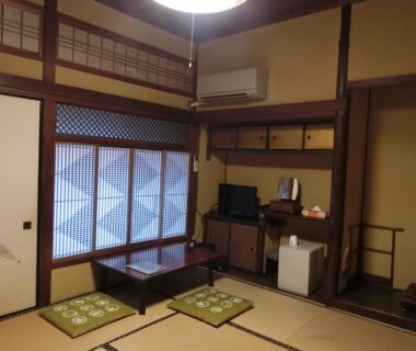Traditional tatami room with low table, floor cushions, shoji window, TV and small fridge at Hoshidekan, Mie