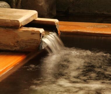 Flowing water from a wooden spout into a traditional onsen tub at Hoshikawakan, Nagano