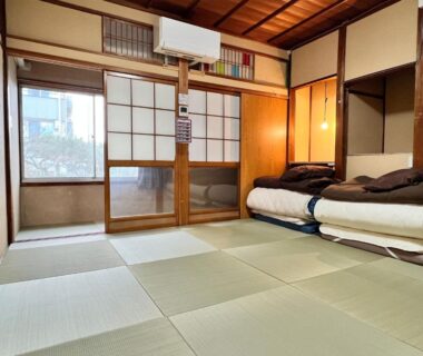 Traditional tatami room with stacked futon bedding and shoji screens at Hostel Murasaki in Gifu, Chūbu