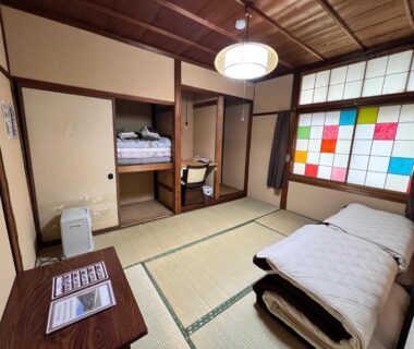 Traditional tatami room with futon, low table, shoji windows and wooden ceiling at Hostel Murasaki in Gifu