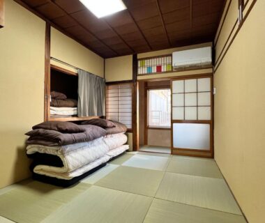 Tatami room with stacked futons and shoji screens at Hostel Murasaki in Gifu Chubu