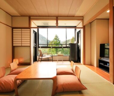 Tatami room with low table, floor cushions, shoji screens and balcony overlooking garden greenery at Hakone Suisen