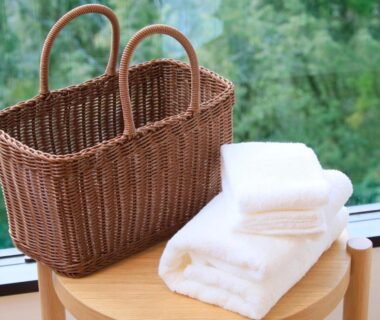 Wicker basket and folded white towels on wooden stool by window overlooking green garden at Hakone Suisen Kanagawa