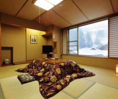 Tatami room with kotatsu and shoji screens at Hot spring inn Snow country in Niigata, snow visible outside window