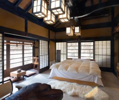 Spacious tatami room with futon bedding, shoji screens, wooden beams and lanterns at Hotakajo, Nagano