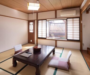 Traditional tatami room with low table, floor cushions, shoji screens and window at Hotakajo in Nagano