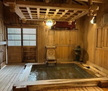 Wood-paneled indoor onsen bath at Hotakajo with lattice ceiling and wooden bench in Nagano