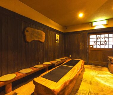 Cozy wooden footbath with stools and low central basin by a traditional entrance at Hotaru no Yado Sendou, Ōita