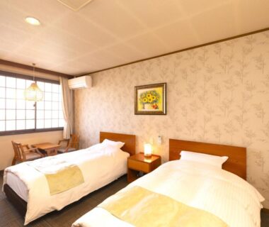 Twin beds with bedside lamp, shoji window and desk at Hotaru no Yado Sendou, Oita
