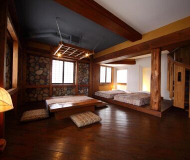 Wooden ryokan room with low table, floor cushions, shoji screens and raised twin beds