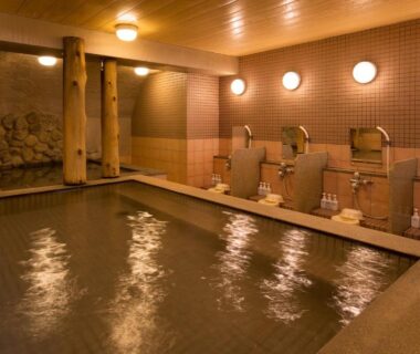 Indoor tiled onsen with washing stations, stools and warm lighting at Hotel Asyl Nara, Kansai