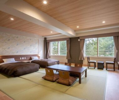 Tatami room with two low beds and central table at Hotel Daiheigen Hokkaidō, views of surrounding trees